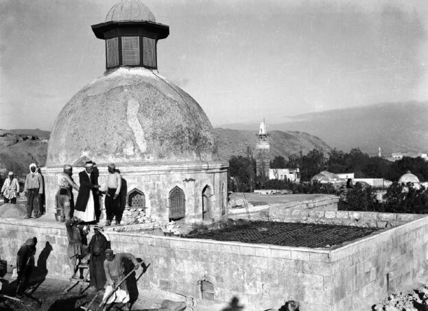 Workers stand around a dome on a rooftop during construction