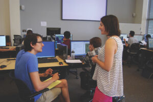 Instructor talking to student in a classroom with computers