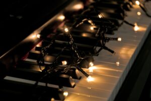 A string of white holiday lights on the keys of a piano
