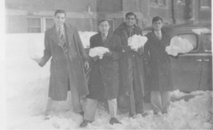 Black and white photo of Indian students standing in the snow and holding chunks of snow.