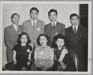 Black and white photo of MIT’s Chinese Students’ Club, showing four men in suits standing behind three seated women.