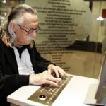 ELIZA creator Joseph Weizenbaum sits at a computer 