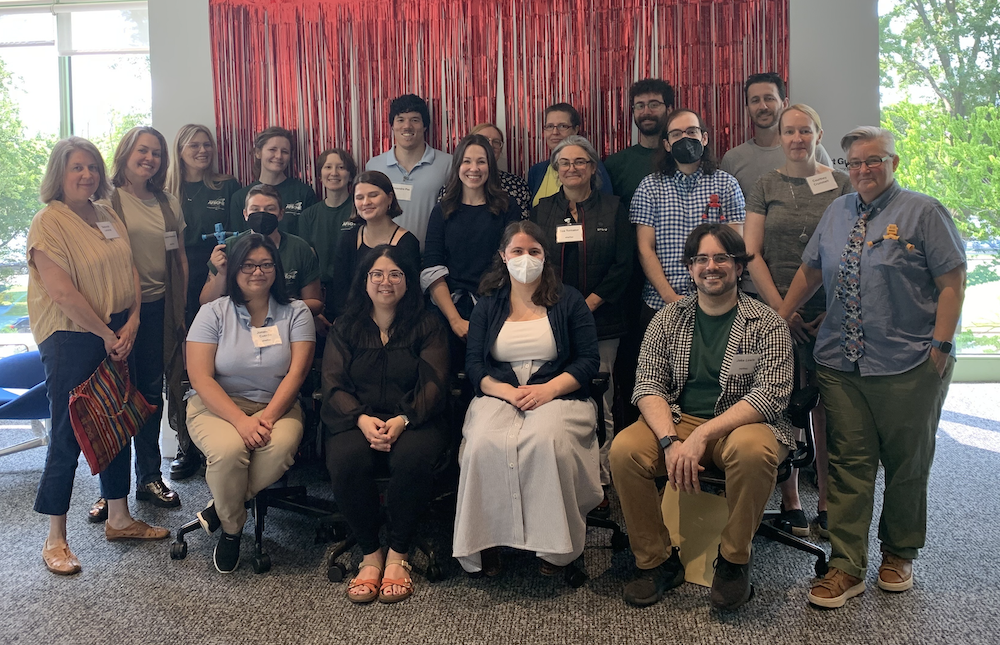 A group of Libraries staff pose for a photo in front of a metallic red fringe backdrop.